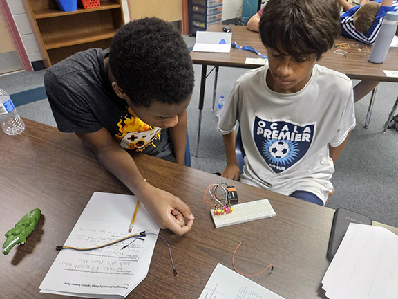 Two middle school students working on a tech project.