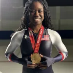 Erin Jackson holds her gold medal while wearing her Team USA racing suit.